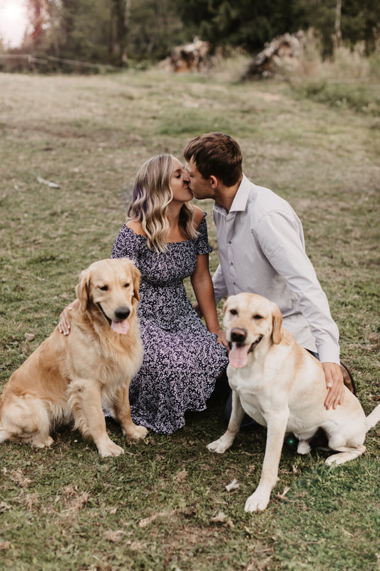 couple kissing with their dogs